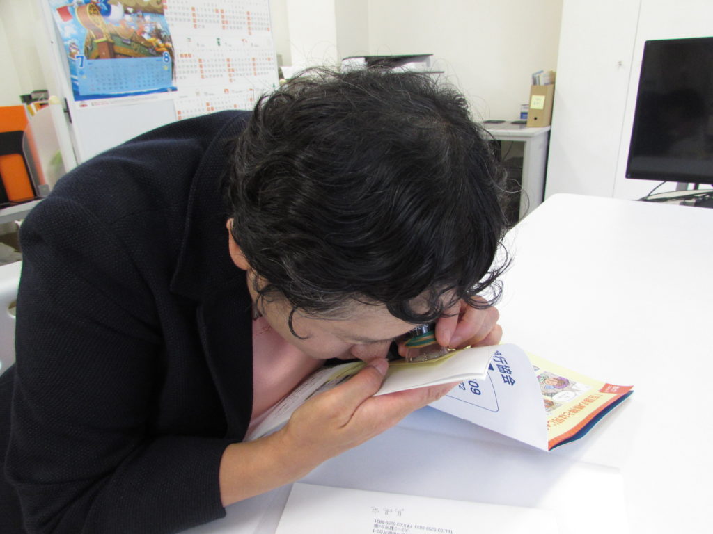 写真:ルーペで冊子を読む女性