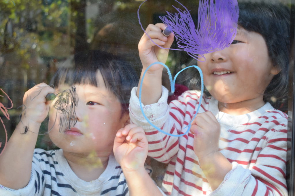 写真：子ども２人が窓に、キットパスでお絵かき