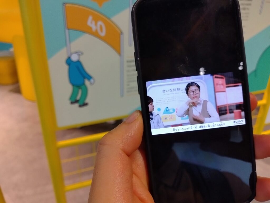 スマホ画面。追いパークを手話で説明する女性の映像