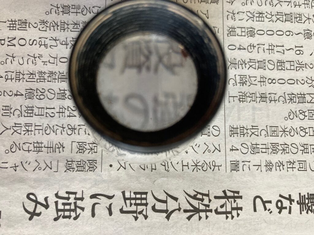 ルーペで新聞の文字を拡大している様子。文字が15倍のサイズで見える