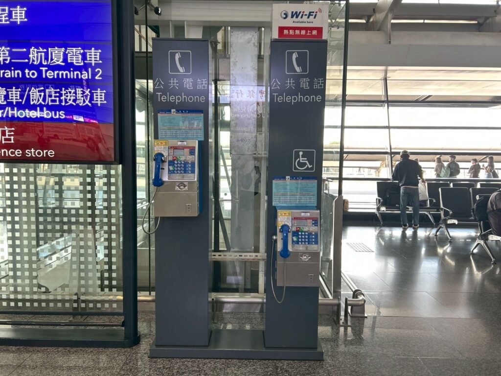 公衆電話が2台並んでおり、片方は子供の背丈ほどの高さに設置されている。電話の上に車椅子のマーク。