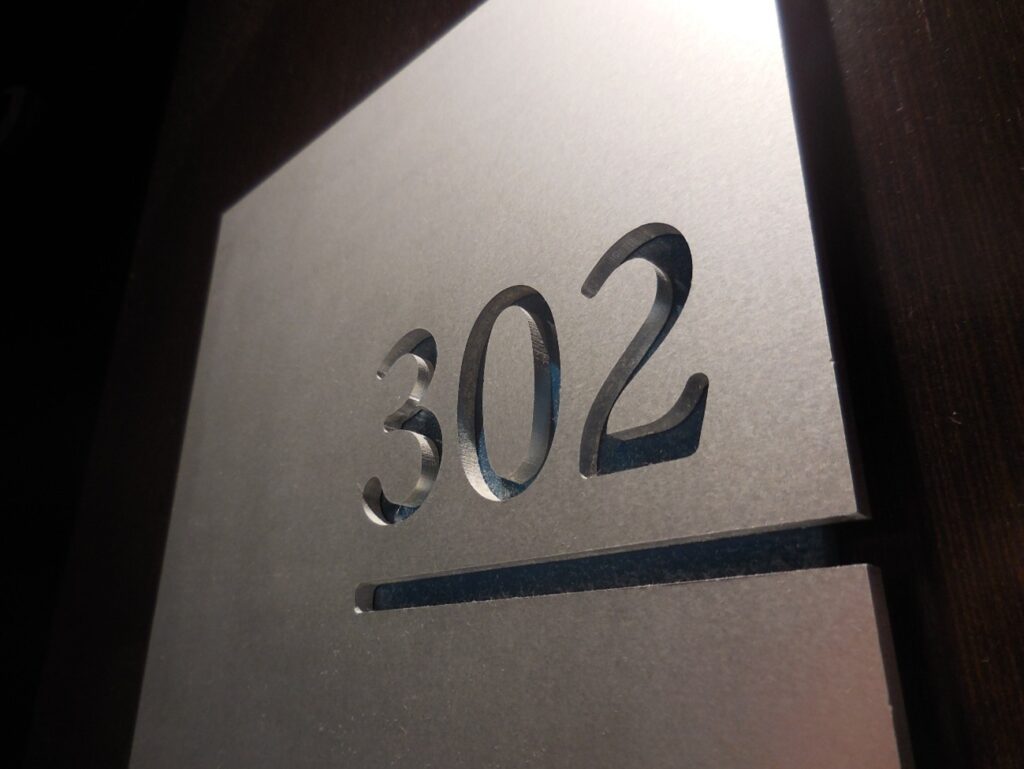 ホテル客室のドアに設置された部屋番号302のプレート。触れて分かるよう立体的にデザインされている