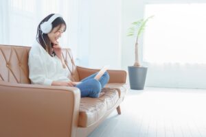 イメージ画像：ノートパソコンを見ながら笑っている、ヘッドホンをつけた女性