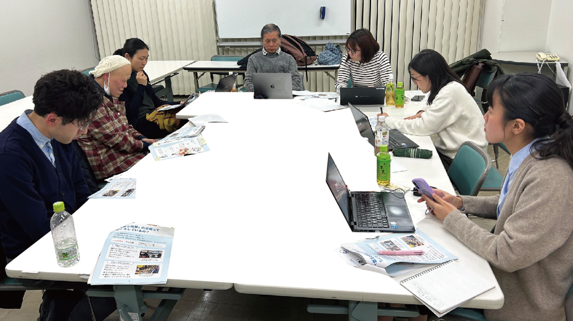 知的障害のある当事者とJICA関係者、ブライトのスタッフが会議室でテーブルを囲み、資料やノートパソコンを使って打ち合わせしている様子。