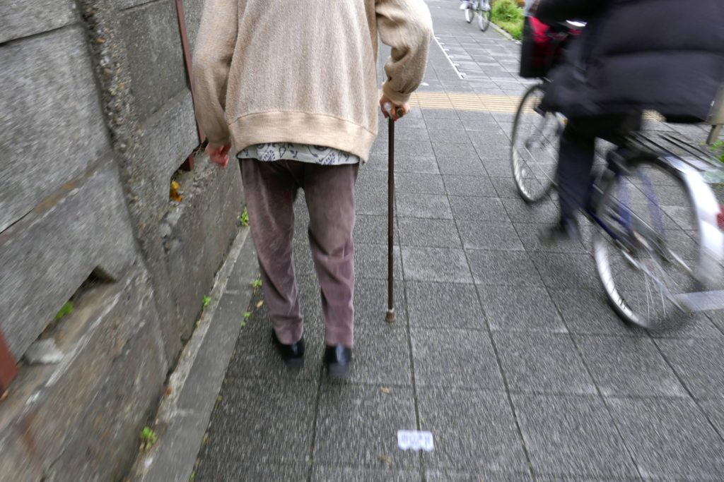 写真：高齢者が杖を付いて歩く様子