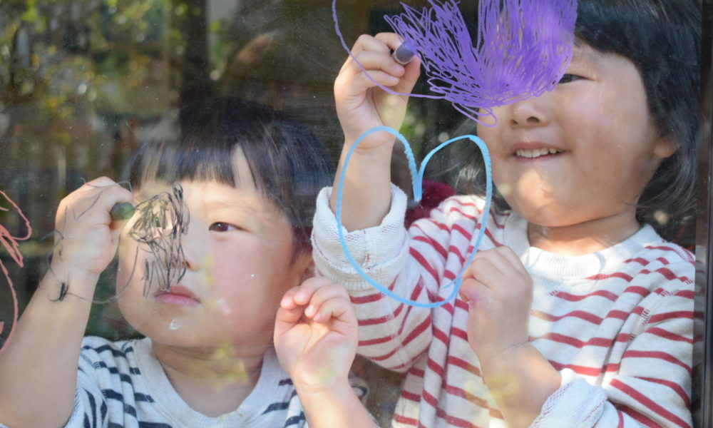 写真：子ども２人が窓に、キットパスでお絵かき