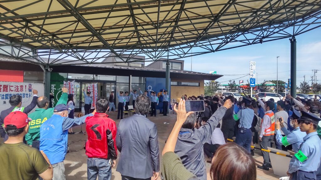 写真：道の駅のイベントスペースにいる人々が拳を上げている